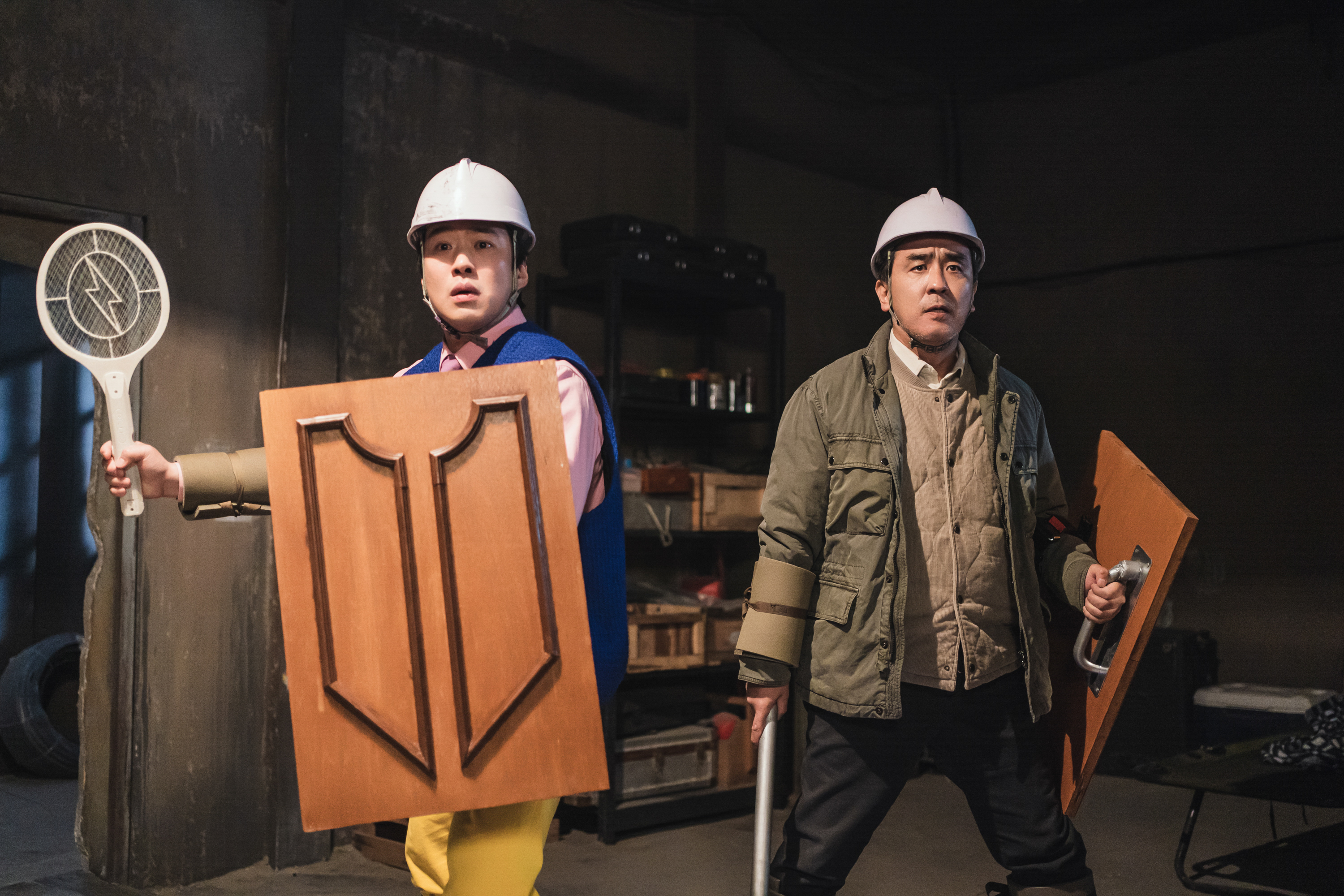 Two men look very silly in office equipment as body armor, holding racquets as weapons, in Chicken Nugget