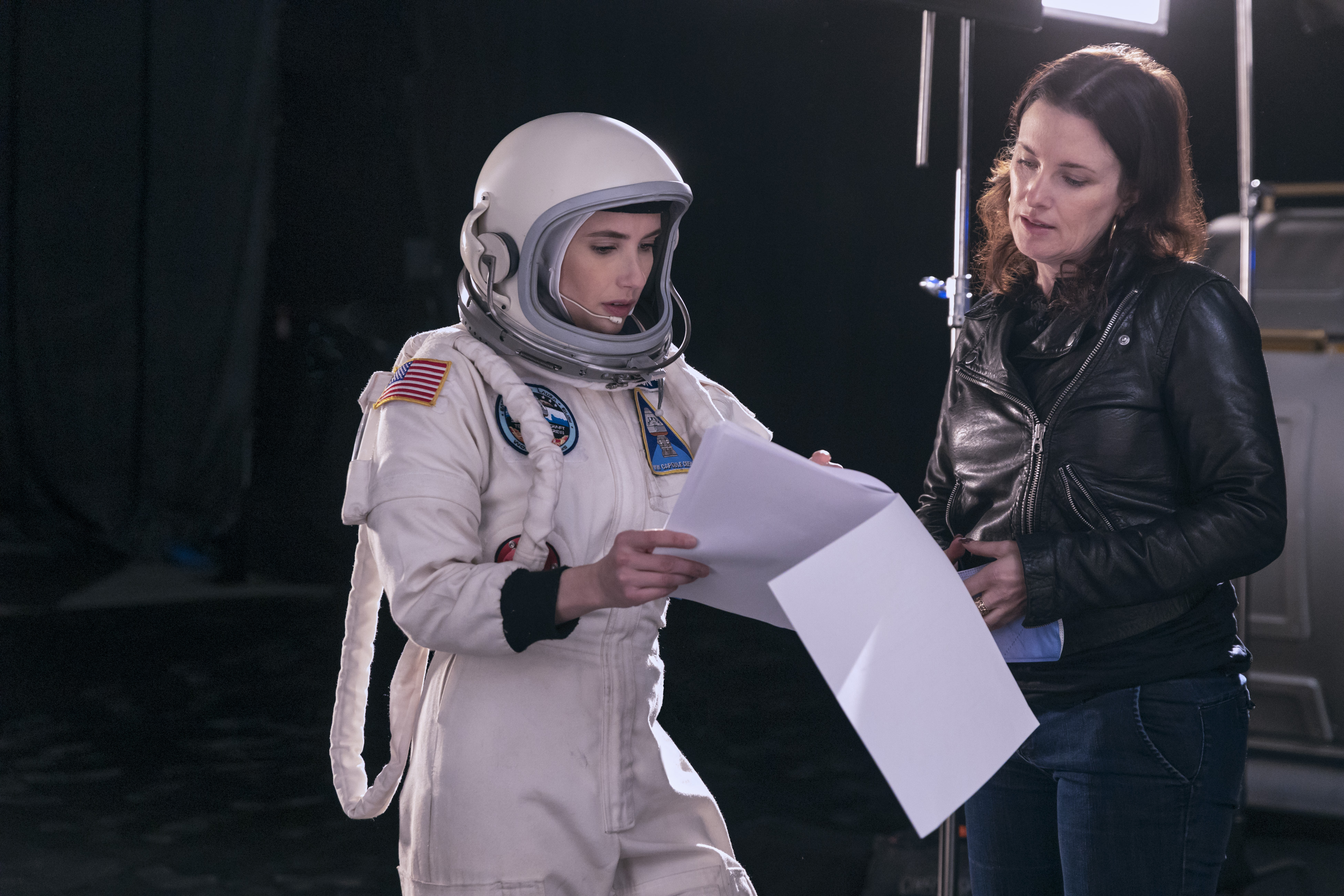 Emma Roberts wearing an astronaut suit going over a script with director Liz W. Garcia