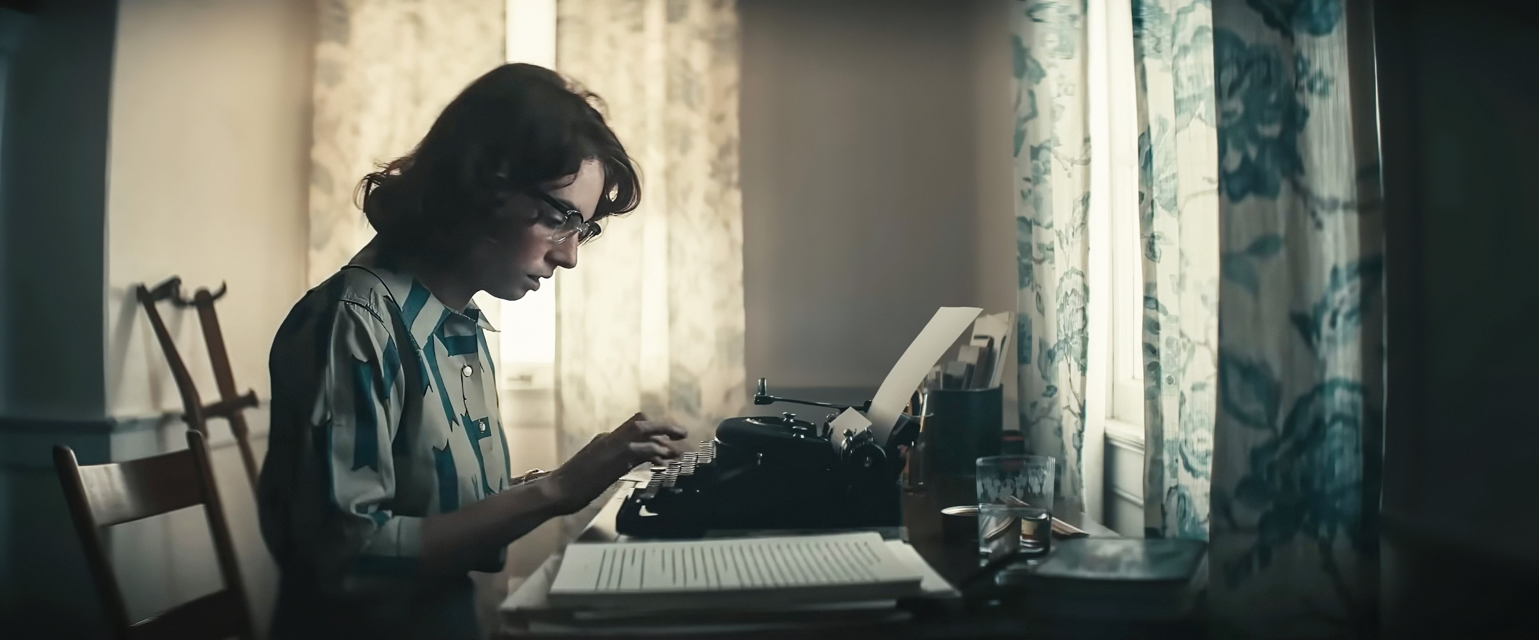 Maya Hawke as Flannery O’Connor, leaning over a typewriter