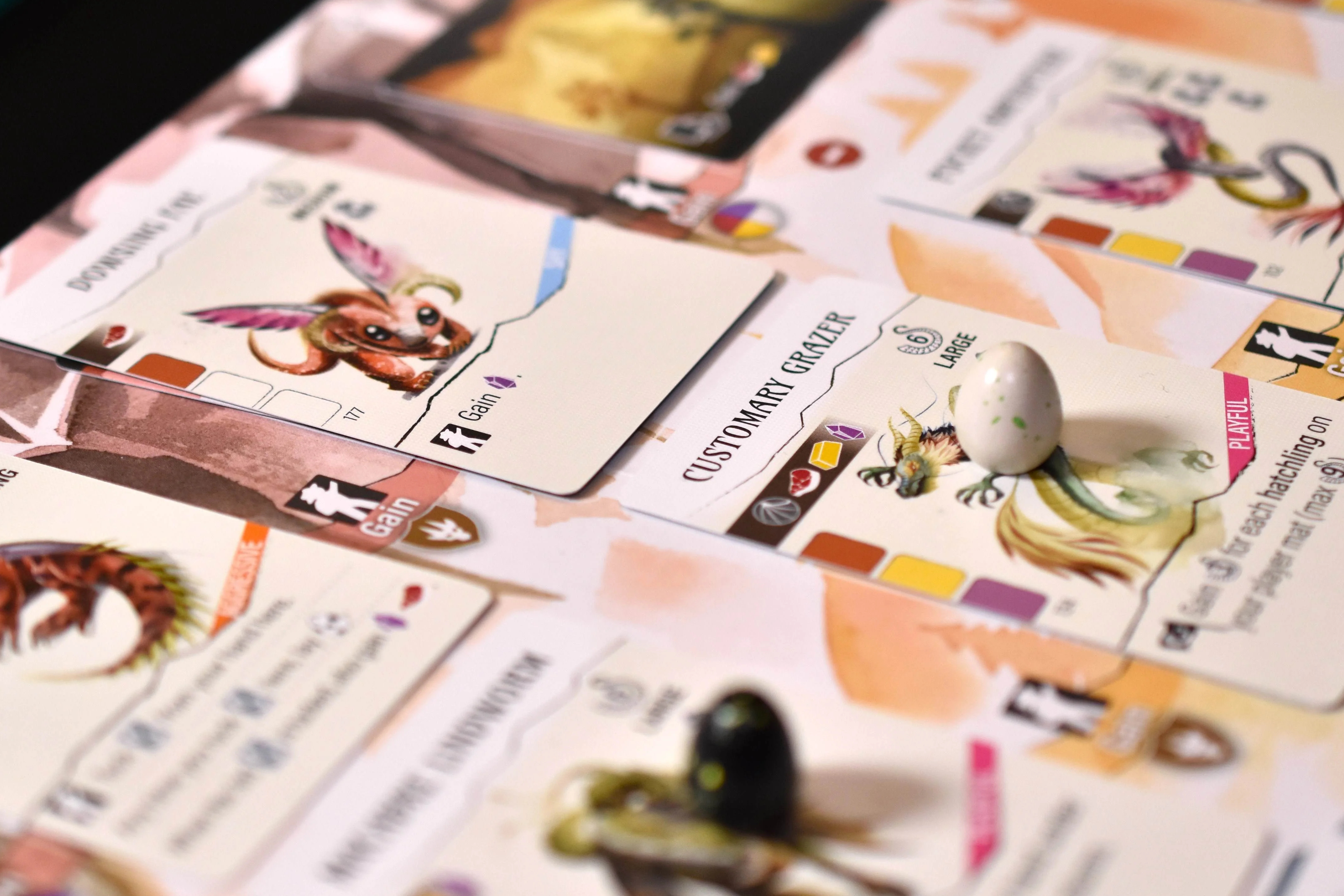 A photo taken of the board game Wyrmspan in play. It shows multiple cards arranged side by side, with game items, like an egg, sitting on top of one.